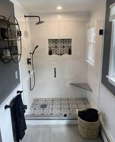 a walk in shower sitting next to a white tiled wall and floor with black accents