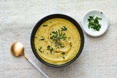 a bowl of hummus next to a spoon on a white towel with a gold spoon