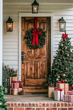 a christmas wreath on the front door of a house with presents around it and two small trees