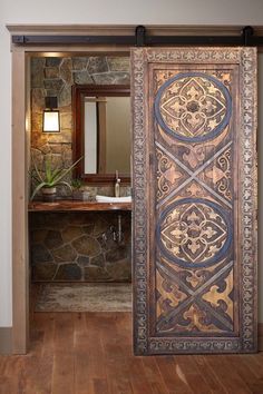 an open door leading to a bathroom with stone walls and wood flooring on the side