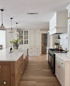 a large kitchen with white cabinets and wood flooring, along with an island in the middle