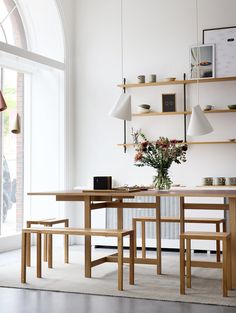 a dining room table with two benches next to it and a vase on the table