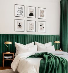 a bedroom with green velvet headboard and pictures on the wall above it, along with white bedding