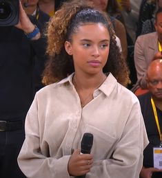 a woman holding a microphone in front of a crowd