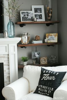 a white couch sitting in front of a fireplace with pictures on the shelves above it