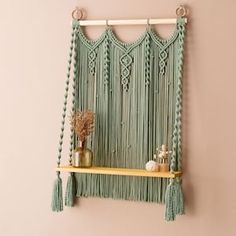 a macrame wall hanging with tassels and vases on a shelf