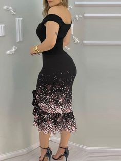 a woman in a black and pink dress is standing against a wall with her hands on her hips