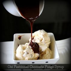 ice cream and chocolate sauce being drizzled over it in a square white bowl