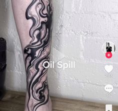 a person's leg with black and white swirls on it, in front of a brick wall