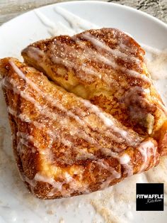 two pieces of french toast on a white plate with icing drizzled over them