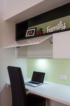 a laptop computer sitting on top of a white desk next to a black leather chair