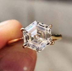 someone is holding an engagement ring that has a square cut diamond in it's center