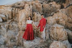 two people standing on rocks holding hands