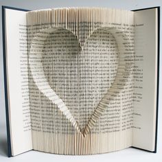 an open book with a heart cut out of it's pages and the pages are folded in half