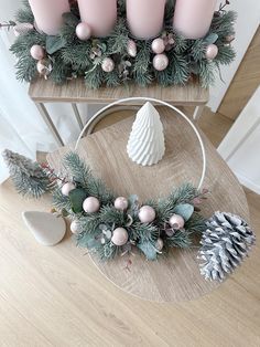 some candles are sitting on a table with pine cones and greenery around it, along with other holiday decorations