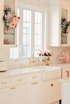 a kitchen with white cabinets and pink flowers