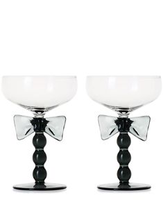 two glass bowls sitting on top of each other with black bases and bows at the tops