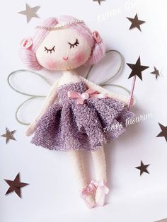 a little doll with pink hair wearing a purple dress and holding a wand in her hand