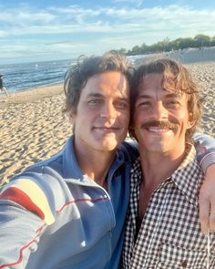 two men standing next to each other on a beach