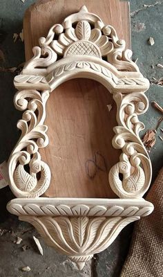 an ornate carved wooden frame on top of a piece of wood