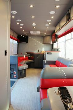 the interior of a bus with red and gray seats, televisions, and lights