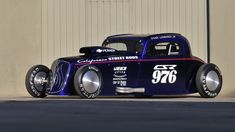 an old model car is parked in front of a garage door with the number seventy on it's side