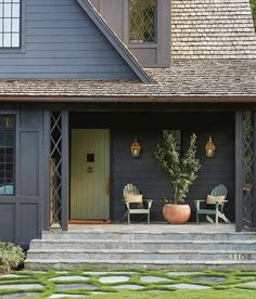 two chairs are sitting on the front porch of a house with stone steps leading up to it