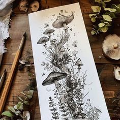 an ink drawing of flowers and mushrooms on paper next to pencils, plants and other items