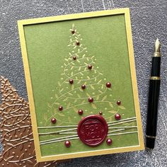 a christmas card with a wax stamp on it and a pen next to the card