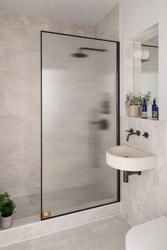 a bathroom with a sink, mirror and shower stall in the corner next to a toilet