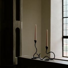 two candles sitting on top of a table next to a window