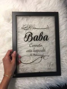 someone is holding up a framed sign with the words baba written in arabic on it