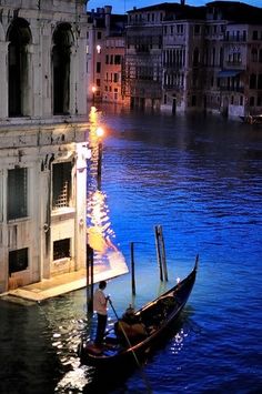 a gondola on the water in front of an old building at night time