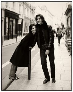 a man and woman standing next to each other on a sidewalk