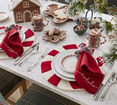 a table set for christmas dinner with plates, silverware and napkins on it