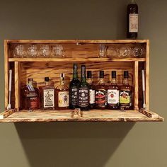 a wooden shelf with liquor bottles and glasses on it, in front of a wall