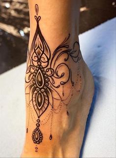 a woman's foot with an intricate tattoo design on the bottom of her leg