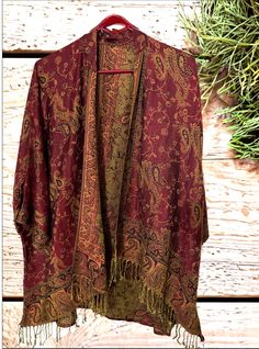 Paisley Pashmina Kimonos | dark Red / Burgundy A fantastic way to stay both stylish and warm. Say goodbye to the struggle of keeping a scarf in place and hello to a chic and comfortable alternative. The free-size kimono offers a fashionable solution to stay comfortable while effortlessly maintaining your style.  Handmade from a delightful and soft pashmina fabric. Features a bohemian style oversized and flowing design. Styled like a cardigan with an open front and generous sleeves . The front is adorned with long fringes at the bottom. A perfect layering piece that effortlessly transitions between casual and dressy occasions. Size: ~~Care Instructions~~ These pashmina jackets can be easily maintained by following a few simple steps Gently hand wash the scarf in cold water Avoid using bleac Luxury Multicolor Pashmina Shawl With Pallu, Luxury Bohemian Pink Shawl, Bohemian Brown Kimono For Fall, Red Bohemian Kimono For Fall, Vintage Fall Shawl, Red Bohemian Outerwear For Festive Season, Red Bohemian Outerwear For Festive Occasions, Red Kimono For Fall, Red One-size Kimono For Fall