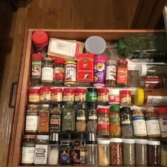 an open drawer filled with spices and condiments on top of a wooden floor