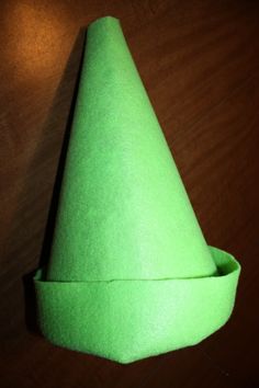 a green paper cone sitting on top of a wooden table next to a light bulb