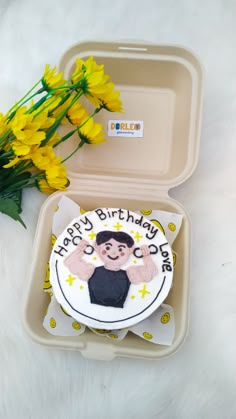 a birthday cake in a plastic container with yellow flowers