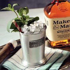 a glass filled with ice and mint sitting on top of a table next to a bottle