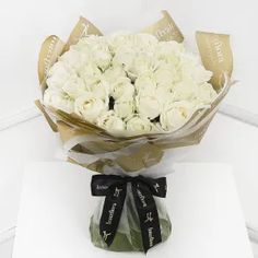 a bouquet of white roses sitting on top of a table