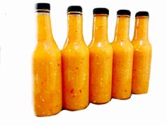 five bottles filled with orange sauce sitting next to each other