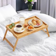 a tray with food on it sitting on top of a bed next to a cup of coffee