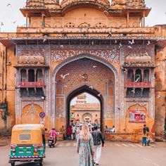 a woman walking in front of an ornate archway