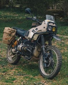 a dirt bike parked on top of a lush green field next to a wooded area