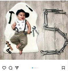 a baby laying on top of a white rug next to some wrenches and tools