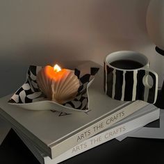 a candle is sitting on top of two books with a cup of coffee next to it