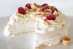 a piece of cake with white frosting and raspberries on top